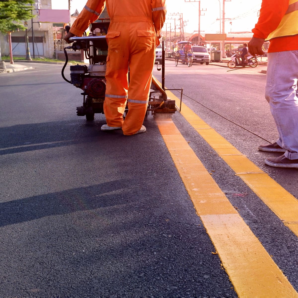 Lucky Stripes crew member in safety gear spraying road striping lines